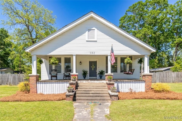 bungalow-style house featuring a porch, fence, and a front lawn