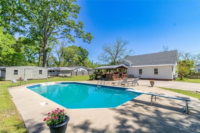 view of swimming pool featuring an outbuilding, a patio area, a fenced in pool, and fence