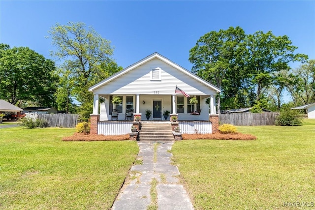 bungalow with a porch, fence, and a front lawn