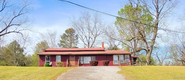 view of front of house with a chimney, driveway, and a front yard
