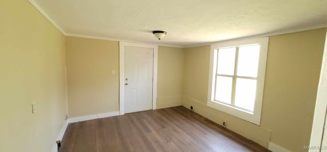 unfurnished room with ornamental molding, a wealth of natural light, wood finished floors, and baseboards