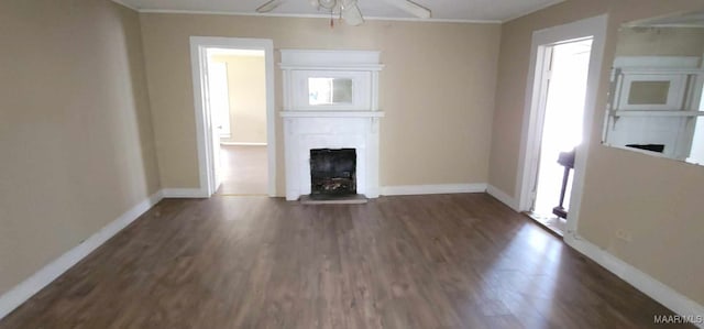 unfurnished living room featuring a fireplace, a ceiling fan, ornamental molding, dark wood-style flooring, and baseboards