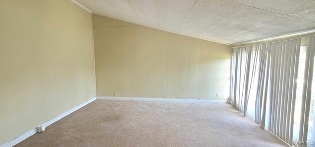 carpeted empty room featuring baseboards, vaulted ceiling, and a textured ceiling