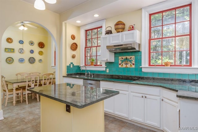 kitchen featuring black electric stovetop, under cabinet range hood, a sink, and a healthy amount of sunlight