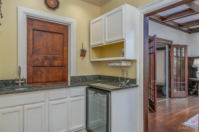 kitchen with dark wood-style floors, white cabinetry, dark stone counters, wine cooler, and a sink