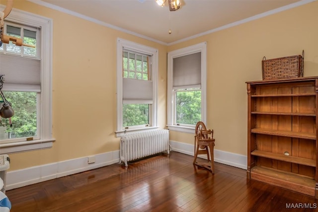 living area featuring ornamental molding, baseboards, radiator, and hardwood / wood-style flooring