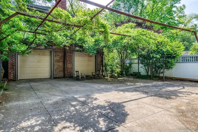 view of patio / terrace featuring a garage, fence, and concrete driveway