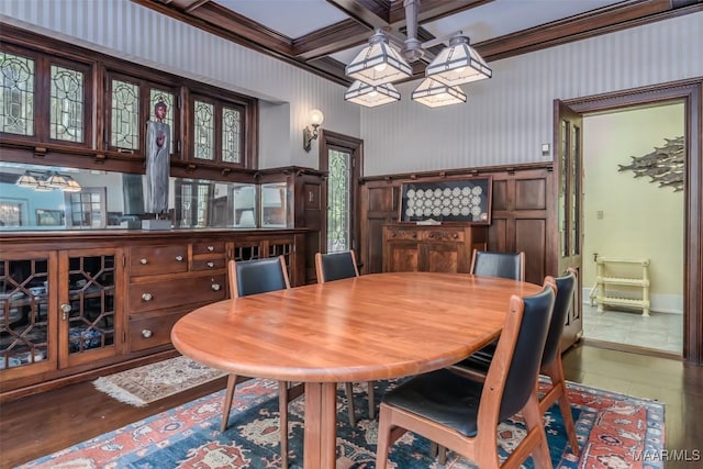 dining area featuring coffered ceiling, a notable chandelier, beam ceiling, and wood finished floors