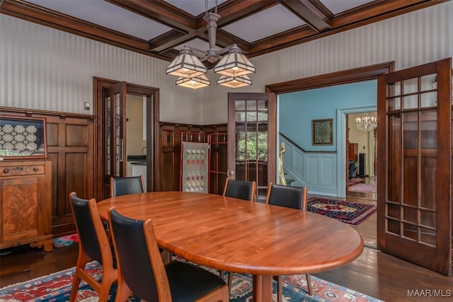 dining space featuring a notable chandelier, crown molding, beam ceiling, wood finished floors, and coffered ceiling