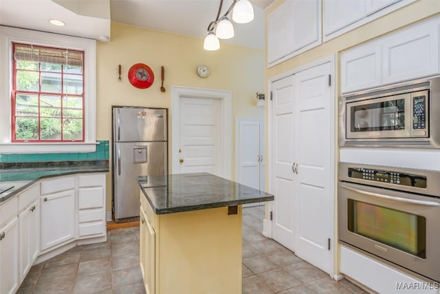 kitchen featuring pendant lighting, white cabinetry, a kitchen island, appliances with stainless steel finishes, and light tile patterned flooring