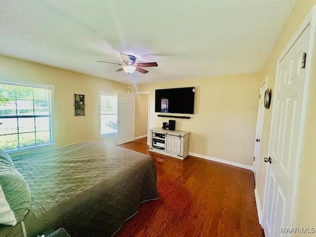 bedroom with dark wood-style flooring, baseboards, a ceiling fan, and a textured ceiling