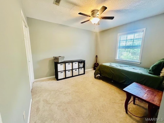 bedroom with a textured ceiling, light colored carpet, a ceiling fan, visible vents, and baseboards