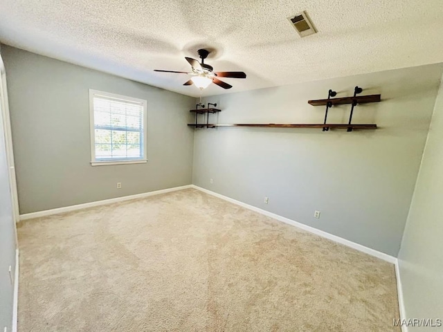 spare room featuring ceiling fan, a textured ceiling, visible vents, carpet flooring, and baseboards