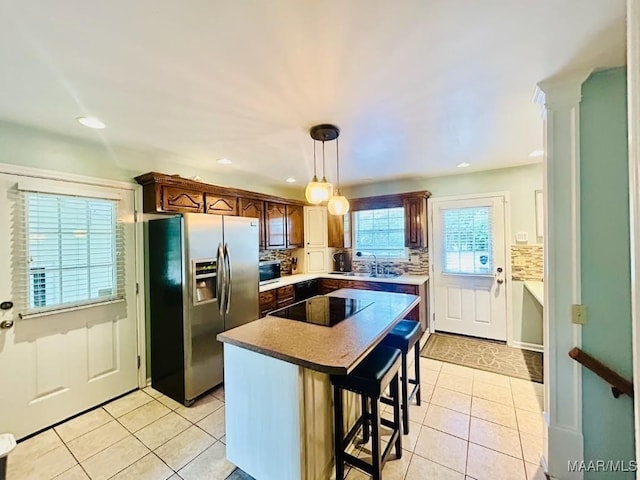 kitchen featuring light tile patterned floors, backsplash, stainless steel refrigerator with ice dispenser, and black electric cooktop