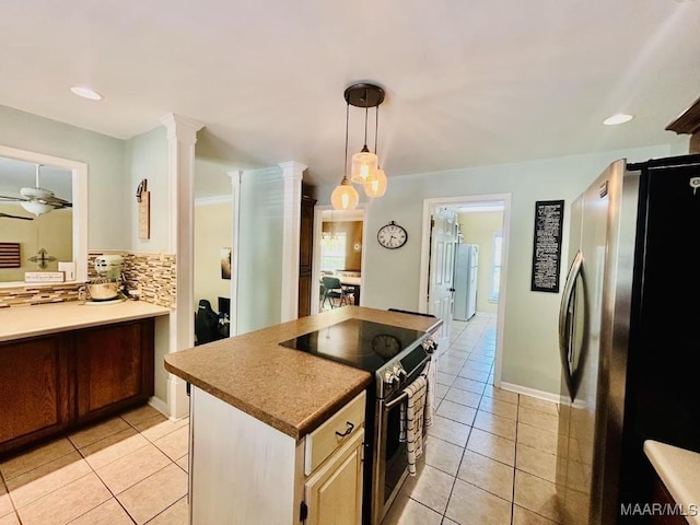 kitchen with decorative backsplash, appliances with stainless steel finishes, light tile patterned floors, and hanging light fixtures