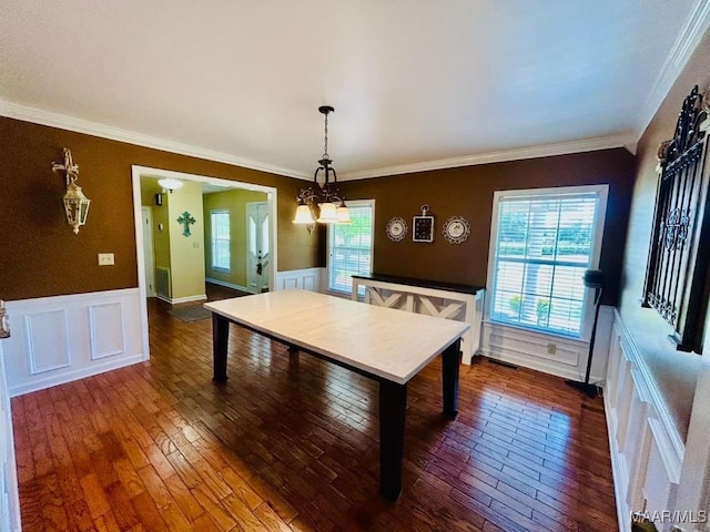 dining area with a decorative wall, dark wood-type flooring, wainscoting, and crown molding