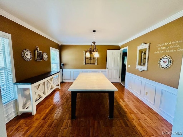 dining space featuring an inviting chandelier, a decorative wall, dark wood-style floors, crown molding, and a wainscoted wall
