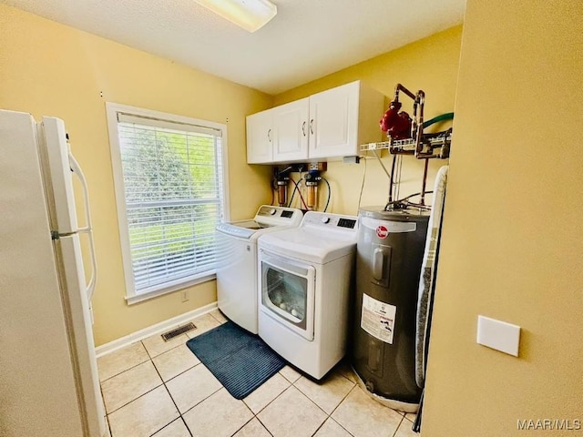 clothes washing area featuring visible vents, light tile patterned floors, water heater, washing machine and clothes dryer, and cabinet space