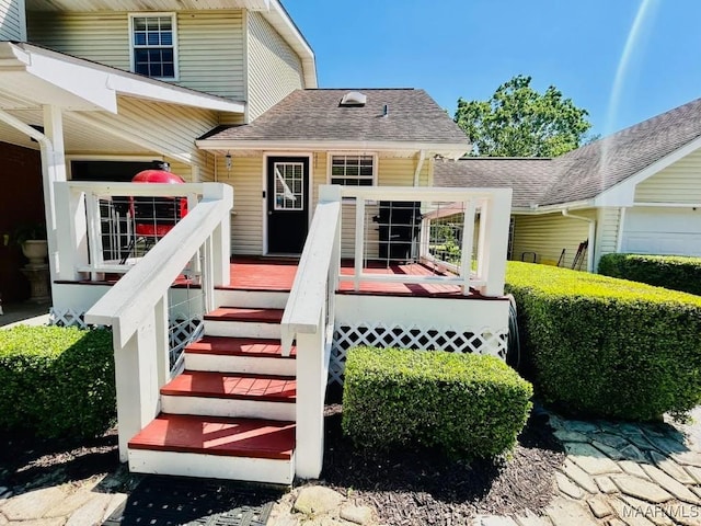 doorway to property featuring a shingled roof and a deck