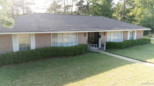 ranch-style home featuring roof with shingles, a front lawn, and brick siding