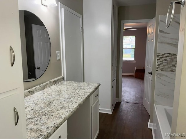 bathroom with vanity, baseboards, a bathtub, a shower, and wood finished floors