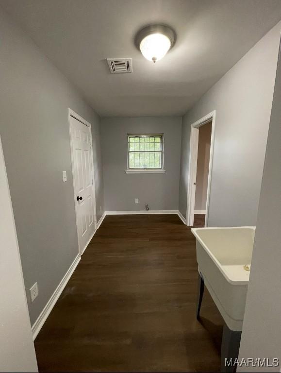 hallway featuring dark wood-type flooring, visible vents, and baseboards