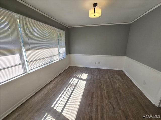spare room featuring wood finished floors, crown molding, and baseboards