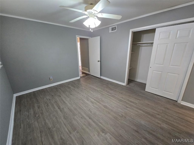unfurnished bedroom featuring wood finished floors, a closet, baseboards, ornamental molding, and visible vents