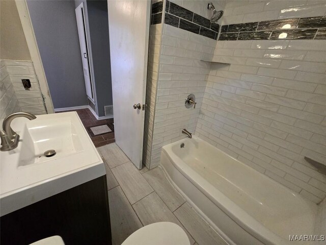full bathroom featuring visible vents, washtub / shower combination, vanity, and toilet