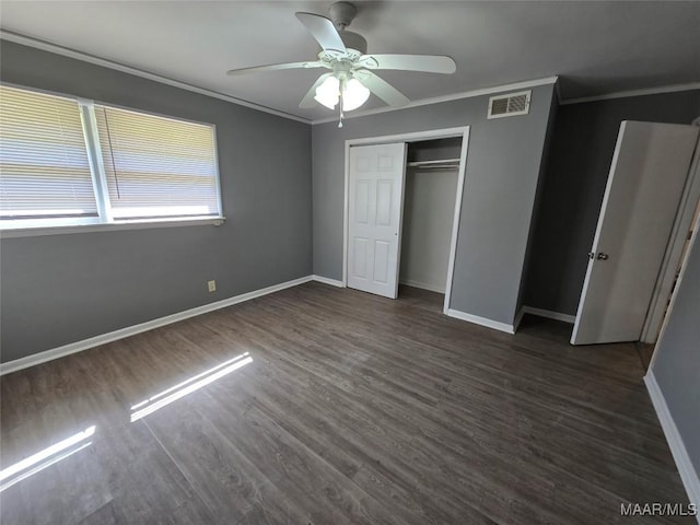 unfurnished bedroom with dark wood-style floors, visible vents, a ceiling fan, ornamental molding, and baseboards