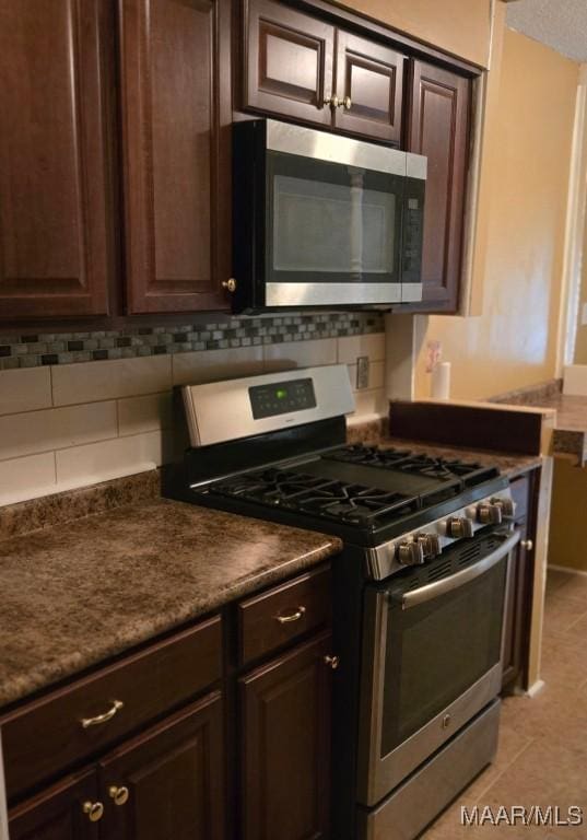 3313 Cross Creek Dr, Montgomery, AL 36116 - kitchen with dark brown cabinetry, backsplash, light tile patterned floors, dark countertops, and appliances with stainless steel finishes