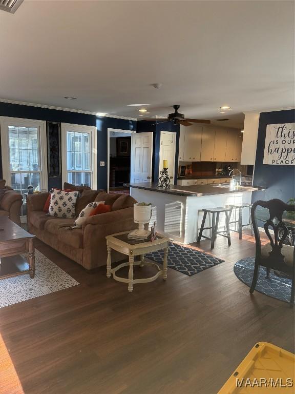 living area with crown molding, wood finished floors, ceiling fan, visible vents, and recessed lighting