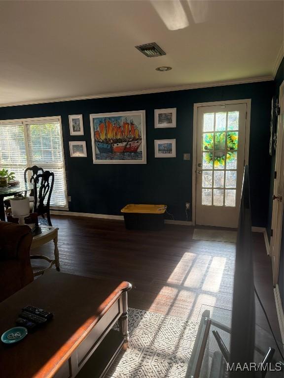living area featuring baseboards, ornamental molding, wood finished floors, and visible vents