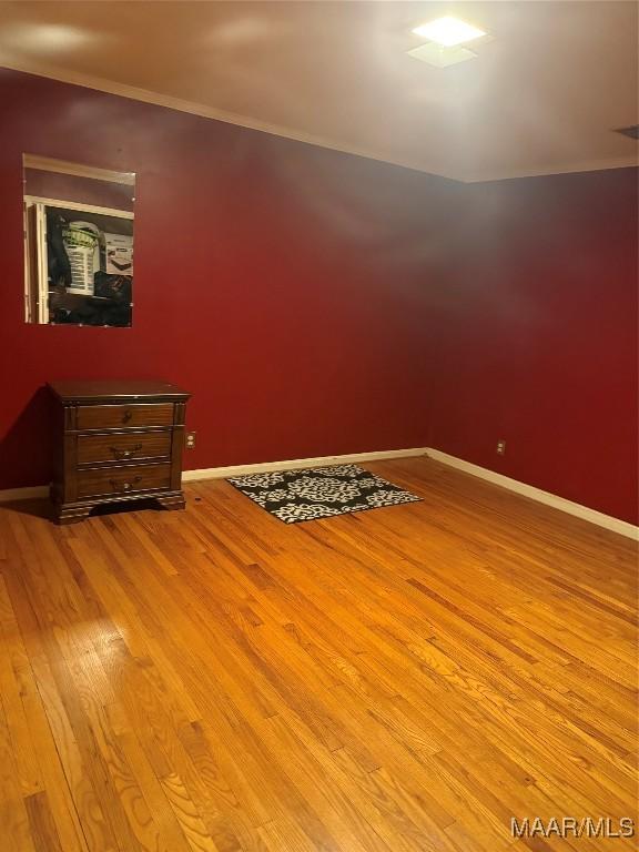 spare room with light wood-type flooring, baseboards, and crown molding