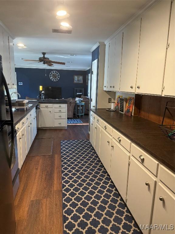 kitchen with dark wood finished floors, ceiling fan, dark countertops, and visible vents