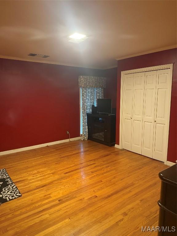 unfurnished bedroom featuring a fireplace, light wood-type flooring, visible vents, and crown molding