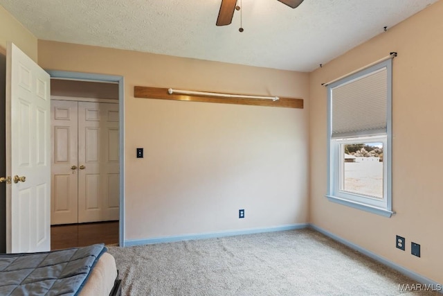 unfurnished bedroom featuring baseboards, carpet floors, a closet, and a ceiling fan