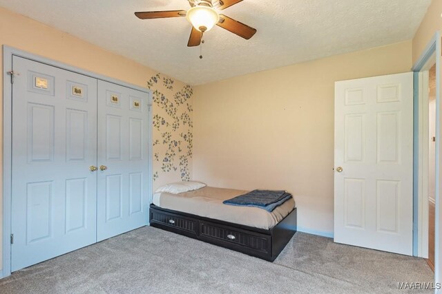 bedroom featuring carpet, ceiling fan, a closet, and a textured ceiling