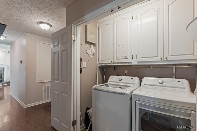 laundry area with washer and clothes dryer, cabinet space, dark wood-style flooring, baseboards, and a textured ceiling