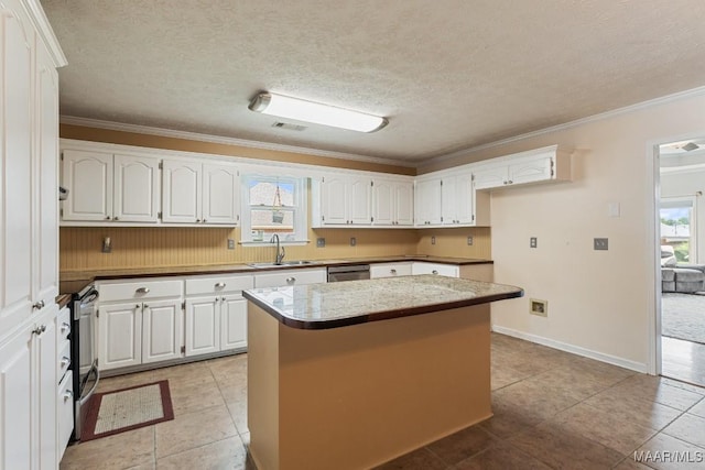 kitchen with a sink, appliances with stainless steel finishes, white cabinetry, crown molding, and a kitchen island