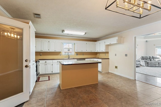 kitchen featuring crown molding, a kitchen island, white cabinetry, a sink, and tile patterned floors