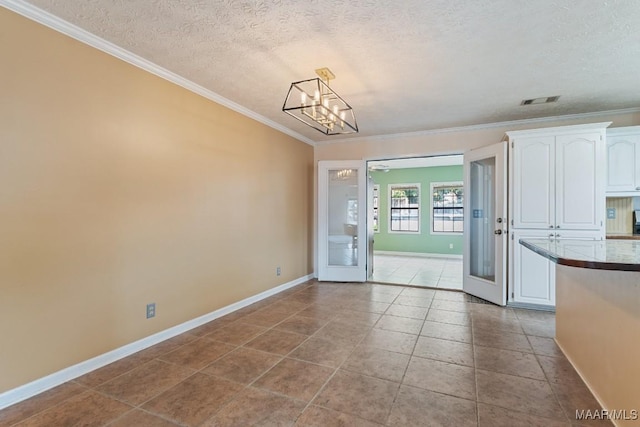 unfurnished dining area with ornamental molding, baseboards, a textured ceiling, a chandelier, and light tile patterned floors