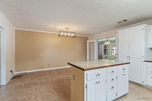 kitchen featuring a kitchen island, white cabinetry, ornamental molding, light countertops, and a textured ceiling