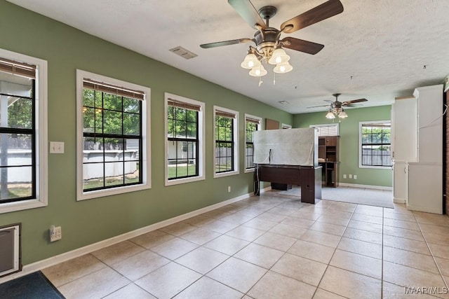 unfurnished living room featuring a ceiling fan, light tile patterned floors, baseboards, and a textured ceiling