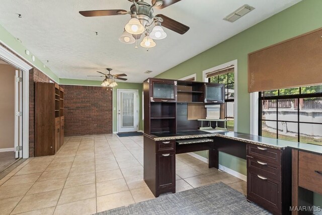 unfurnished office with ceiling fan, light tile patterned flooring, brick wall, and baseboards