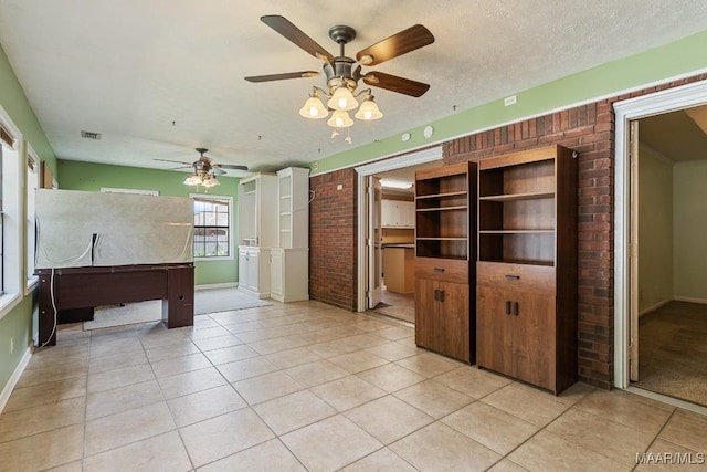 unfurnished living room featuring brick wall, ceiling fan, baseboards, and light tile patterned floors