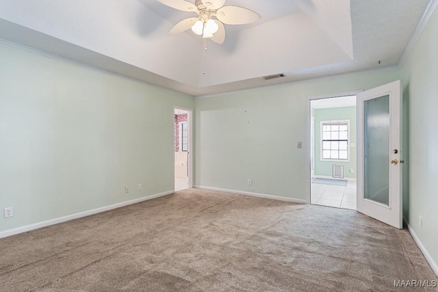 carpeted spare room with ornamental molding, a ceiling fan, a raised ceiling, and baseboards