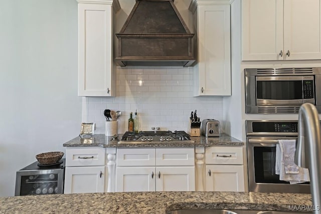 184 Houston St, Prattville, AL 36066 - kitchen featuring white cabinets, stainless steel appliances, dark stone countertops, backsplash, and custom exhaust hood