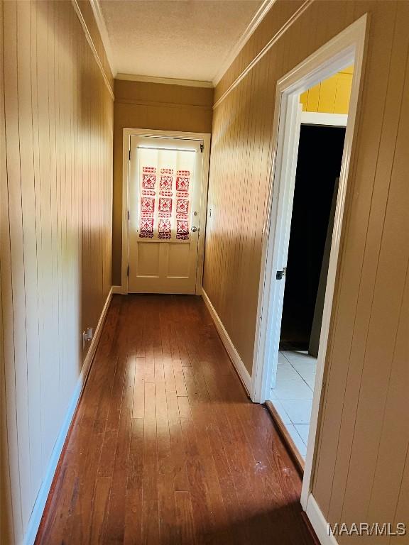 interior space featuring baseboards, hardwood / wood-style flooring, wooden walls, and crown molding