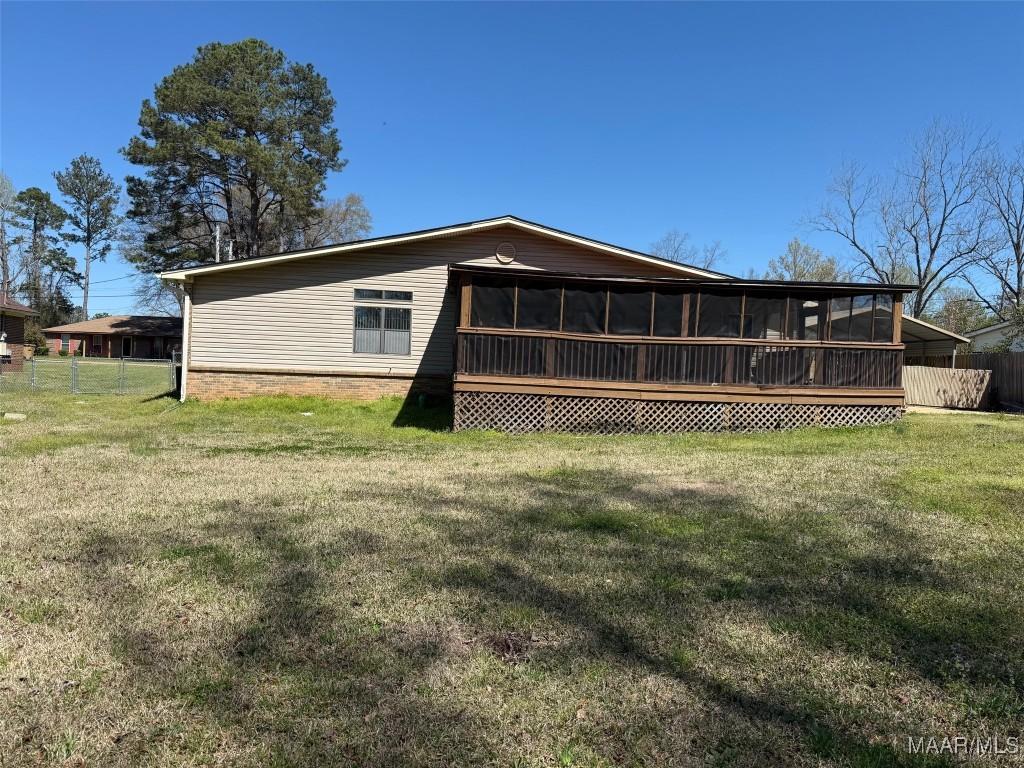 back of property featuring a yard, a sunroom, and fence